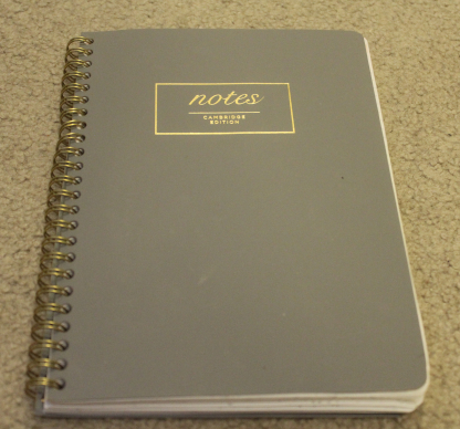 Image shows a small gray notebook. On its front, the notebook says "notes" and "Cambridge edition."