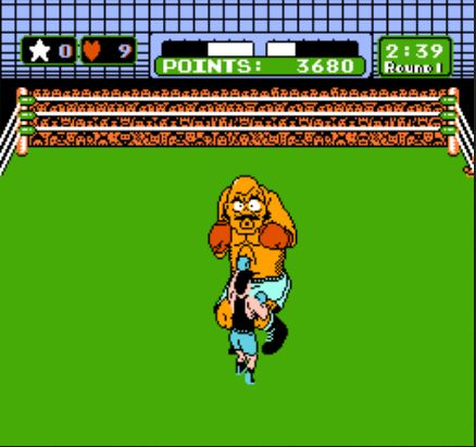 A screenshot of the video game Mike Tyson's Punch-Out!! from the 8-bit Nintendo Entertainment System. It shows a boxing ring, wherein the player, Little Mac, is jabbing an opponent, Bald Bull, with his left fist. Bald Bull is making a pained expression.