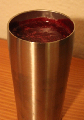 The image shows a completed beet root smoothie in a metal cup atop a wooden dresser.