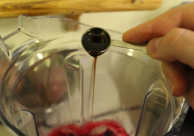 The photo shows my hand pouring, from a filled teaspon, yacon syrup into the blender container