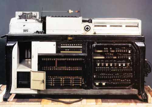 The color photo shows, sitting atop a wood board or table, an IBM Hollerith tabulator, which looks like a strange combination of a telephone, computer, sewing machine, and typewriter.