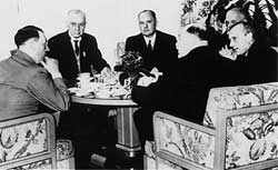 The black-and-white photo shows men in suits sitting around a table.