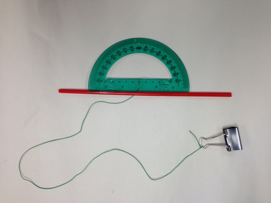 The image shows a DIY clinometer fashioned from a protractor, a straw, clear tape, a straw, and a binder clip.