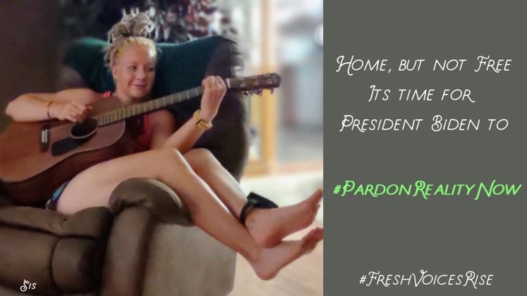 The image shows Reality Winner on home confinement, sitting on a recliner smiling and playing acoustic guitar. She's wearing an ankle monitor. She's not using a pick, but her bare hand, to strum. 