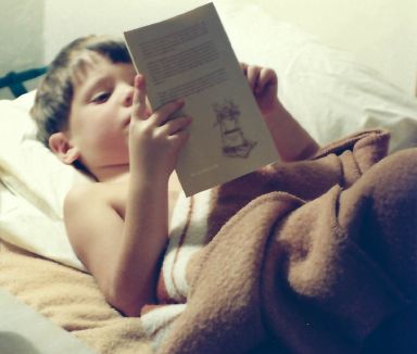 The photo shows a child in bed reading. The child is me.