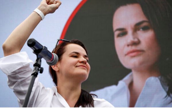 Image shows the opposition leader in front of a microphone stand, raising her fist 