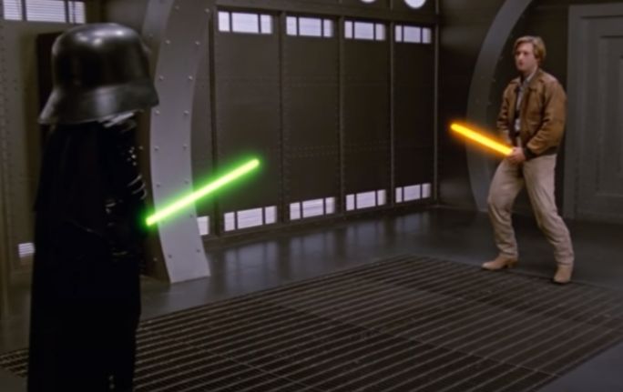 Climactic scene from Spaceballs where, in the evil spaceship, the lovable rogue character and the Darth Vader character face off as if in fencing, but hold their base of their lightsabers just above their clothed, uh, groins. 
