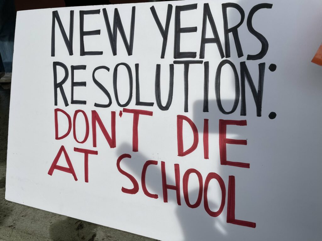 Protest sign reads: "New years resolution: Don't die at school"