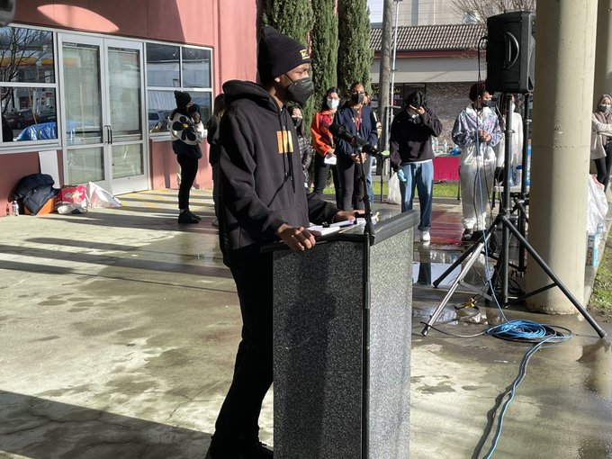 Photo of student leader talking into microphone at podium