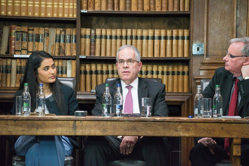 This is a color photograph of the whistleblowing panel showing the moderator on the left, Ewen MacAskill on the right, and in the center, Shedd looking surprised and off guard
